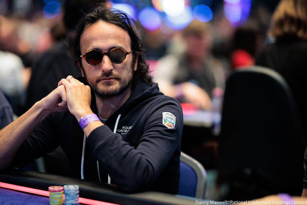 Davidi Kitai concentré à la table de poker lors de l'EPT Monaco 2023, lunettes de soleil, mains croisées