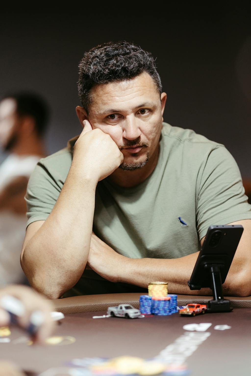 Joueur de poker concentré, poing sous le menton, analysant la table avec des jetons devant lui