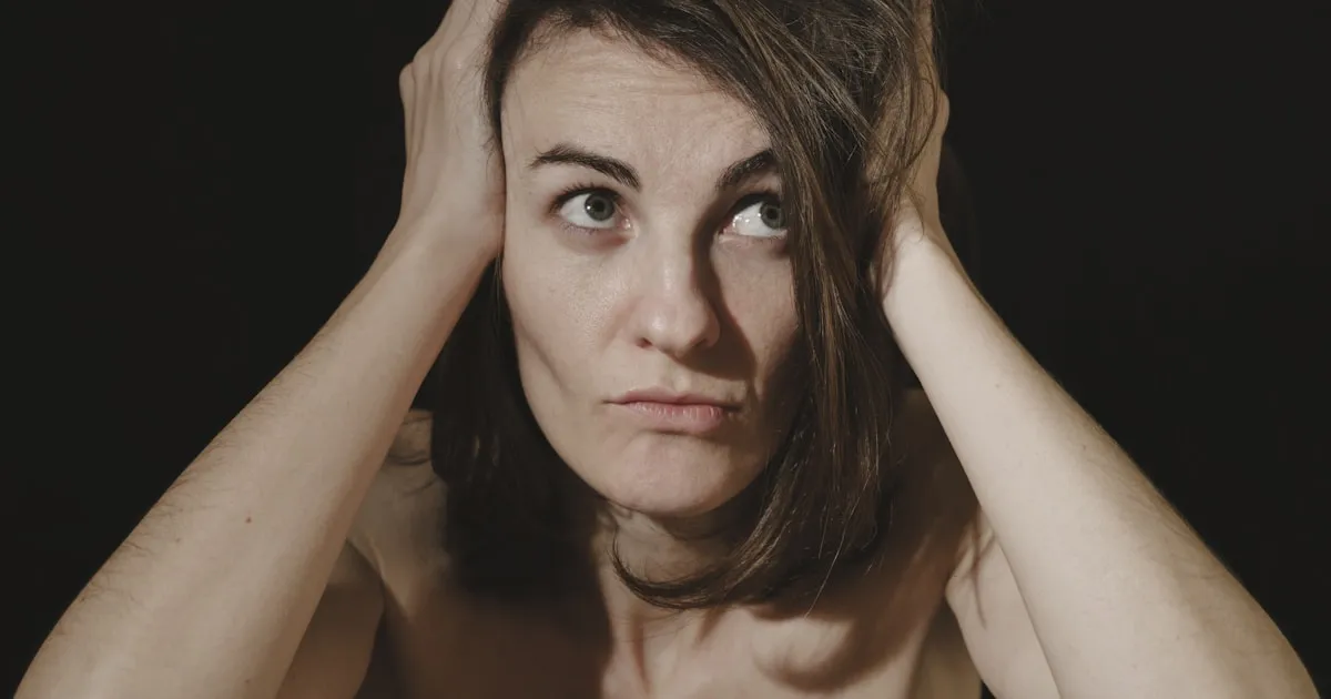 Femme se tenant la tete, regard dans le vide, illustrant la charge mentale et l'hyperactivite interne du TDAH feminin